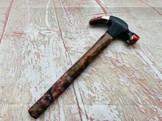 an old hammer laying on top of a white wooden floor next to a red and black object