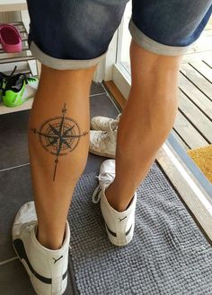 a person with a compass tattoo on their leg, standing in front of a door