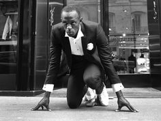 a black and white photo of a man in a tuxedo squatting down