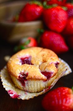 two strawberry muffins sitting on top of each other next to some strawberries