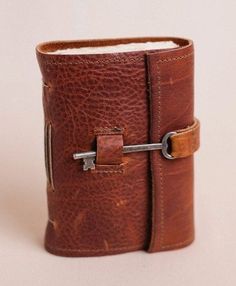 a brown leather book with a key on the front and two holes in the middle