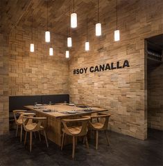 a restaurant with wooden tables and chairs in front of a brick wall that reads soy canalia