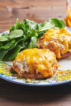 two meat patties with cheese and spinach on a plate