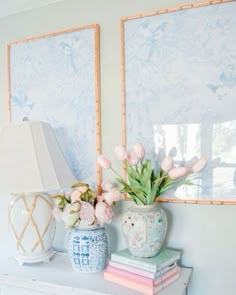 two vases with flowers are sitting on a shelf next to books and a lamp