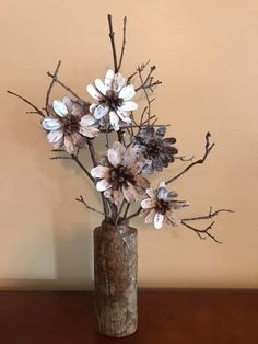 a vase filled with flowers sitting on top of a wooden table next to a wall