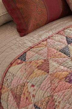 a close up of a bed with a quilt on it's cover and pillows