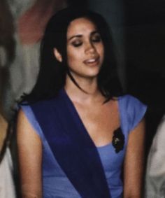 a woman in a blue dress standing next to other people