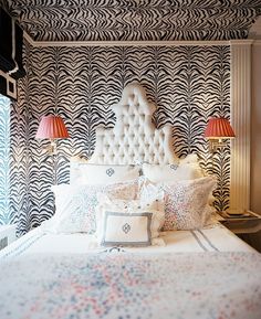 a bed with two lamps on either side of the headboard and pillows in front of it