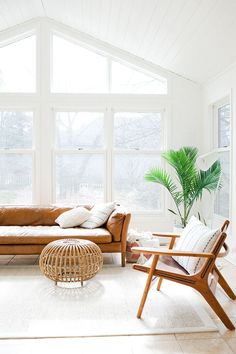 a living room with couches, chairs and a potted plant in the corner