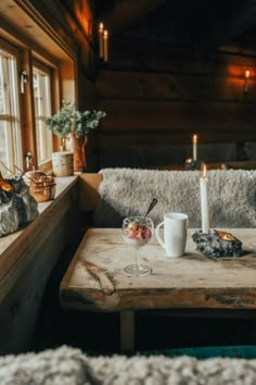 a wooden table topped with two cups filled with liquid next to candles and other items