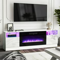 a living room with a television and fireplace in the center, surrounded by white furniture