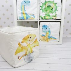 three storage bins with dinosaurs painted on them, one in white and the other in blue