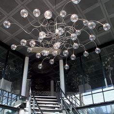 a large chandelier hanging from the ceiling in a room with glass walls and stairs