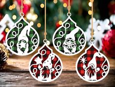 three christmas ornaments hanging from strings on a wooden table next to a pine cone and holiday decorations