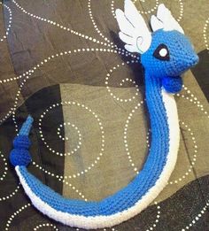 a crocheted blue and white dragon on a pillow