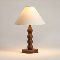 a wooden table lamp with a white shade on the base and a light in the middle