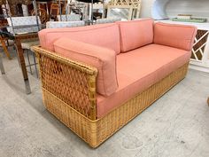 a wicker couch sitting on top of a floor next to a table and chairs