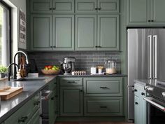 a kitchen with green cabinets and stainless steel appliances