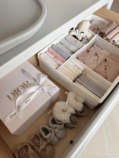 an open drawer with shoes and clothing in it next to a white box on a counter