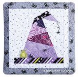 a quilted wall hanging with a purple hat on it