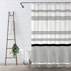 a white shower curtain with black and white stripes on it in front of a brick wall