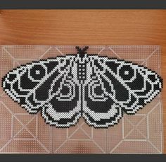 a beaded butterfly sitting on top of a wooden table