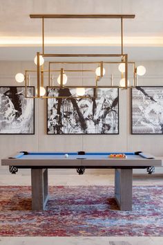 a pool table in the middle of a room with paintings on the wall behind it