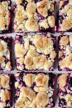 several squares of blueberry crumbs are arranged in rows on a white surface