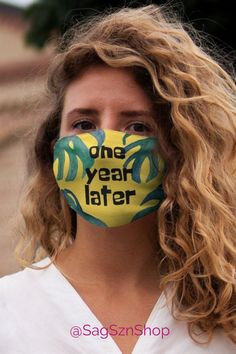 a woman wearing a face mask with the words one year later painted on it