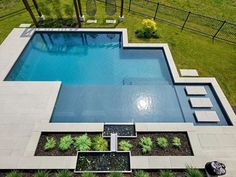 an aerial view of a swimming pool surrounded by greenery and landscaping in the backyard