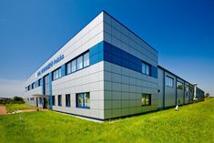 an office building sitting on top of a lush green field