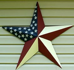 a red, white and blue star hanging on the side of a building with siding