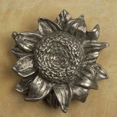 a metal sunflower is shown on a brown table top, with the petals still attached to it