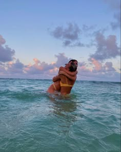 a woman in the ocean hugging her friend