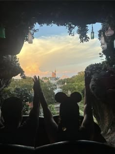 two people are sitting in a vehicle with their hands up