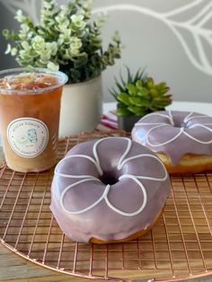 two glazed donuts sitting on top of a cooling rack next to a cup of coffee