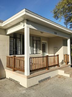 the front porch of a small house with wooden railings and wood balconies