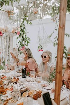 three women sitting at a table with food and drinks in front of them, all wearing sun glasses