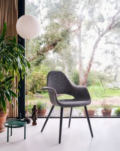 a chair sitting in front of a window next to a potted plant and table