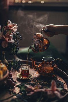 a person pouring tea into a cup on top of a table