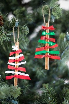 two christmas trees made out of strips of red, green and white paper hanging from a tree