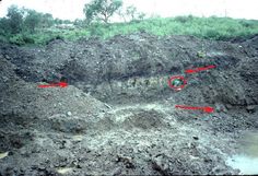 an open pit with red arrows pointing to the ground