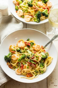 two plates of pasta with shrimp and broccoli