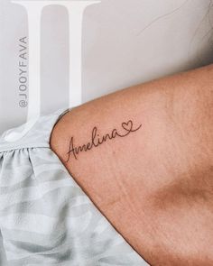 the back of a woman's shoulder with an arm tattoo that reads, amelina