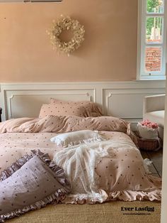 a bed with pink sheets and pillows in front of a window