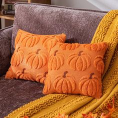 two orange pillows sitting on top of a couch