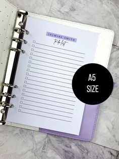 a5 size planner book with purple trim and black circle on the cover, next to a