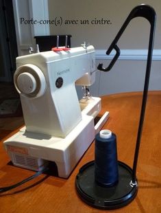 a sewing machine sitting on top of a wooden table next to a spool of thread