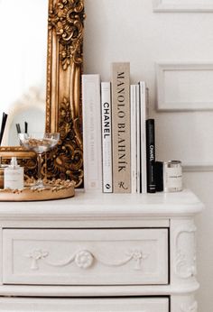 a white dresser topped with books and a mirror