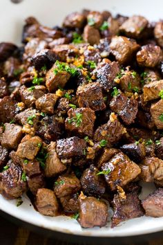 a white bowl filled with meat and garnished with parsley